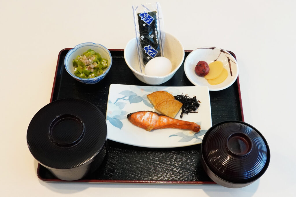 焼き鮭、卵、味噌汁、海苔、漬物、小鉢が並ぶ日本の伝統的な和朝食セット
